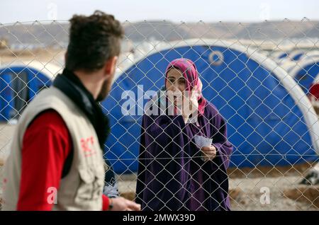 An Iraqi woman who fled the fighting between Iraqi security forces and Islamic State militants waits for humanitarian aid at a camp for internally displaced people, in Khazir, near Mosul, Iraq, Monday, Dec. 5, 2016. The U.N.'s refugee agency distributed aid to dozens of Iraqi families uprooted from their homes in and around the city of Mosul. They are among the nearly 5,500 people living in tents in the camp east of Mosul where the battle to retake the city from the Islamic State group is underway. (AP Photo/Hadi Mizban)