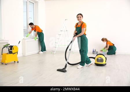 Team of professional janitors in uniforms cleaning room Stock Photo