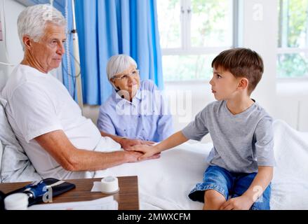 The earnest optimism of youth. a sick man in a hospital being comforted by his grandson. Stock Photo