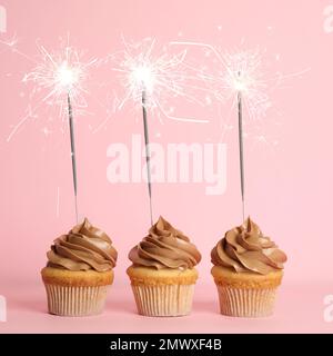 Birthday cupcakes with sparklers on pink background Stock Photo