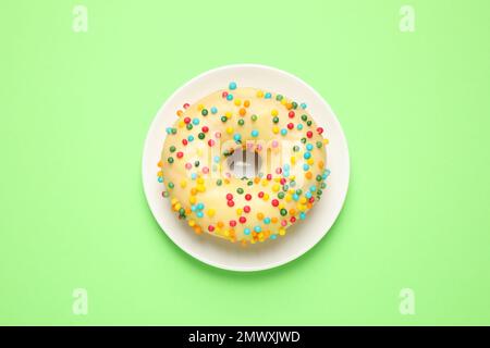 Delicious glazed donut on green background, top view Stock Photo