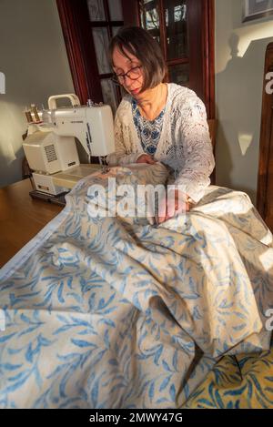 Woman at sewing machine making curtains. Stock Photo