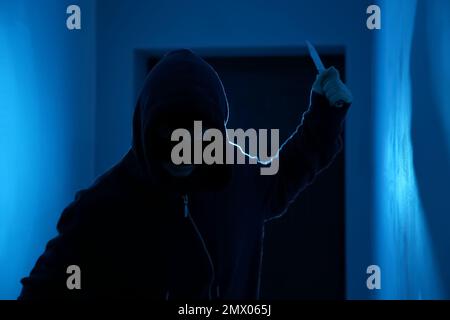 Man with knife in dark room. Dangerous criminal Stock Photo