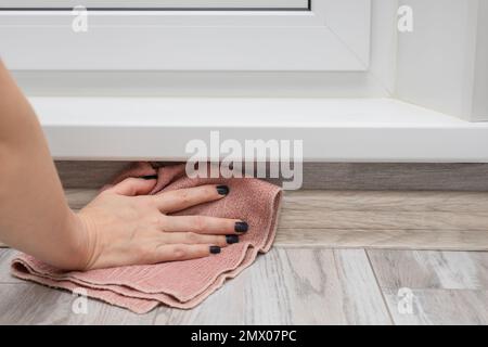 a woman washes the floor in a hard-to-reach place. wiping the skirting board with a rag. House cleaning. Stock Photo