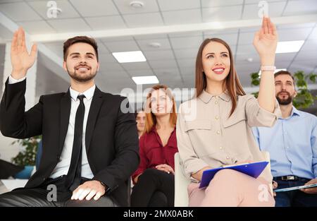 People raising hands to ask questions at business training indoors Stock Photo