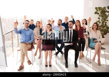 People raising hands to ask questions at business training indoors Stock Photo