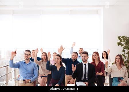 People raising hands to ask questions at business training indoors Stock Photo