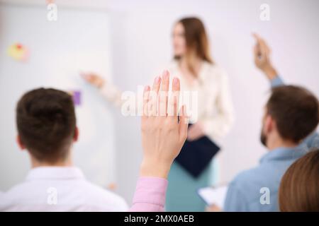 Woman raising hand to ask question at business training indoors, closeup Stock Photo