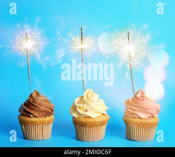 Birthday cupcakes with sparklers on light blue background Stock Photo