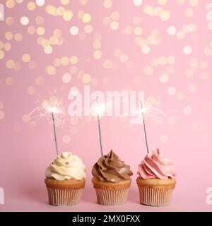 Birthday cupcakes with sparklers on pink background Stock Photo