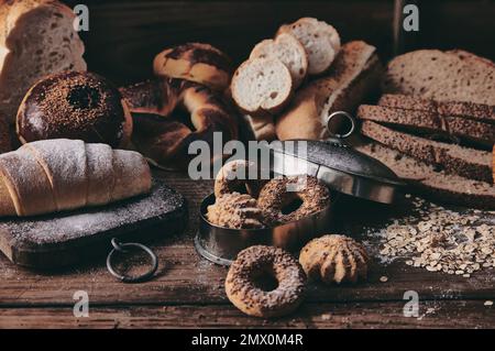 Assorted types of freshly baked buns and slices of Turkish bread served on table in kitchen of bakery with pastry Stock Photo