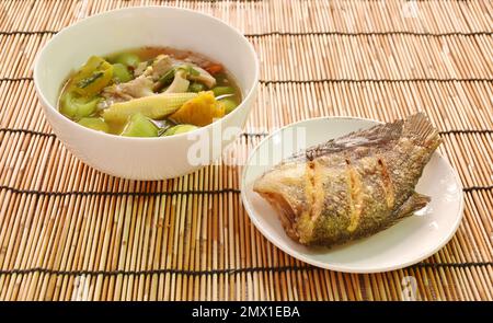 boiled spicy mixed vegetable curry soup on bowl with deep fried snake skin catfish or gourami on dish Stock Photo