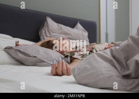 Young brunette between crumpled sheets in a king size bed Stock Photo