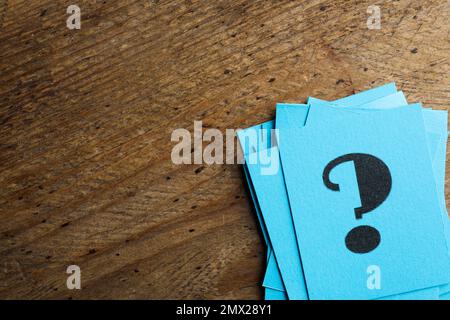 Blue paper cards with question mark on wooden background, top view. Space for text Stock Photo