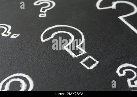 Question marks drawn with chalk on blackboard, closeup Stock Photo