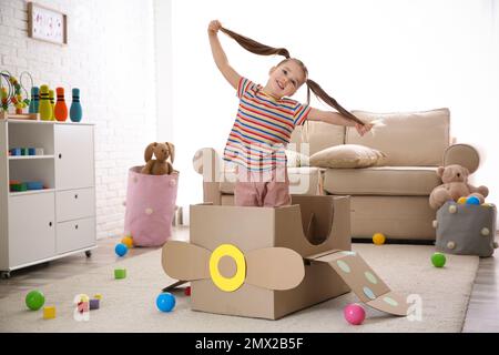 Cute little child playing with cardboard plane at home Stock Photo