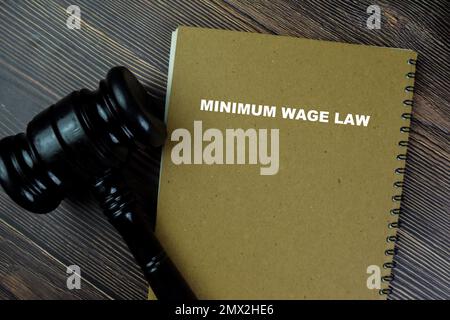 Concept of Minimum Wage Law write on a book with gavel isolated on Wooden Table. Stock Photo