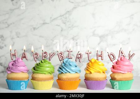 Birthday cupcakes with burning candles on table against marble background. Space for text Stock Photo