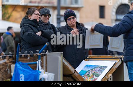 three adult women choosing a painting to an artist who sells his works on the street in rome, italy. concept city life Stock Photo