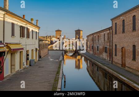 Perspective view of a Comacchio canal with the famous three-way bridge in the background. Comacchio, province of Ferrara, Emilia Romagna, Italy. Stock Photo