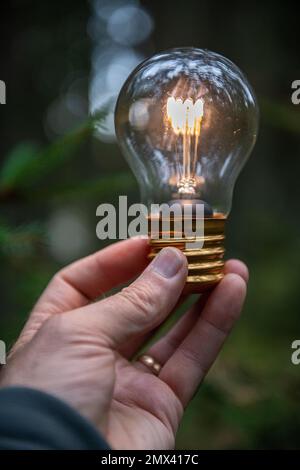 Close-up of hand holding lit light bulb Stock Photo