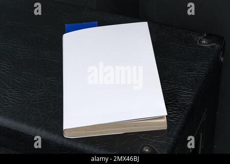 Blank white book cover template with blue bookmark on top of the black speaker cabinet. Clipping path. Stock Photo