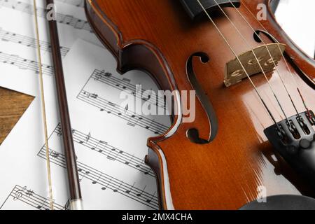 Beautiful violin, bow and note sheets on table, closeup Stock Photo