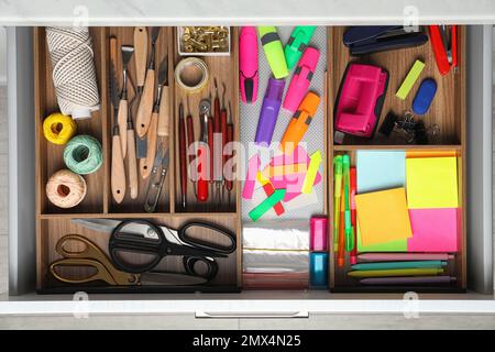 Stationery and sewing accessories in open desk drawer, top view Stock Photo