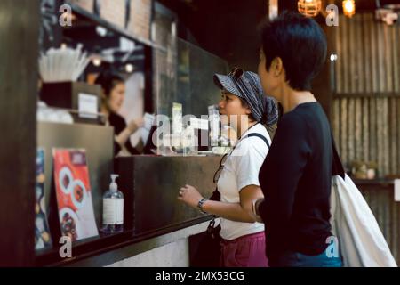 Two women friends placing an order to take out in a coffee shop. Stock Photo