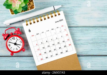 June 2023 Monthly desk calendar for the organizer to plan 2023 year with alarm clock and pen on wooden table. Stock Photo