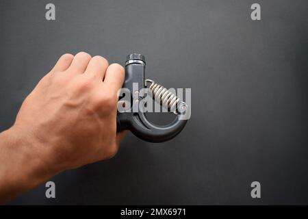 Hand exercising, squeezing a handgrip, man gripping hand exercise gripper. Stock Photo