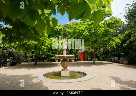 A fountain in the middle of a gravel courtyard surrounded by  Indian Bean trees or Catalpa bignonioide in the gravel courtyard at the Collector Earl's Stock Photo