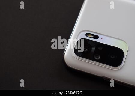 Smartphone quad camera module. New modern white smartphone with quad camera module isolated on black background. Closeup of smartphone camera lens Stock Photo