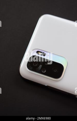 Smartphone quad camera module. New modern white smartphone with quad camera module isolated on black background. Closeup of smartphone camera lens Stock Photo