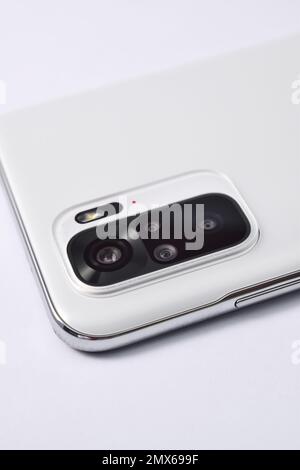Smartphone quad camera module. New modern white smartphone with quad camera module isolated on white background. Closeup of smartphone camera lens Stock Photo