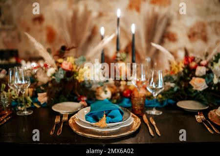 Exquisite, elegant golden and blue table set decoration in moody dark colors Stock Photo