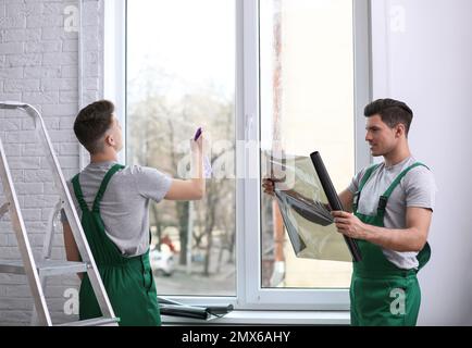 Professional workers tinting window with foil indoors Stock Photo