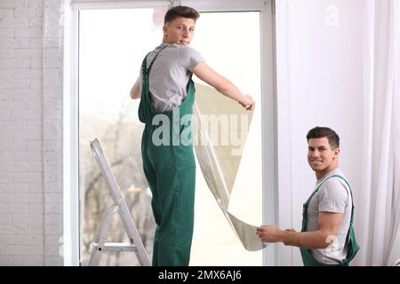 Professional workers tinting window with foil indoors Stock Photo