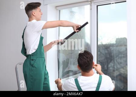 Professional workers tinting window with foil indoors Stock Photo