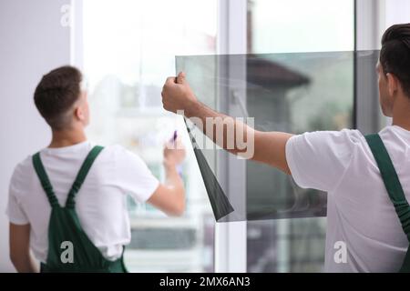Professional workers tinting window with foil indoors Stock Photo