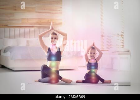 Mother and daughter with chakra points practicing yoga at home. Healing energy Stock Photo