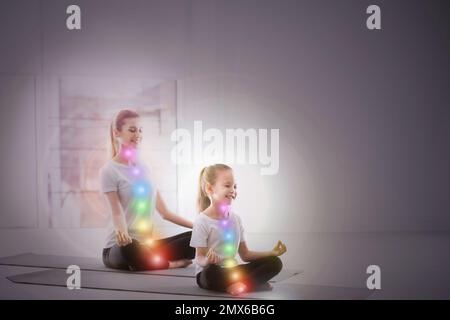 Mother and daughter with chakra points practicing yoga in studio. Healing energy Stock Photo