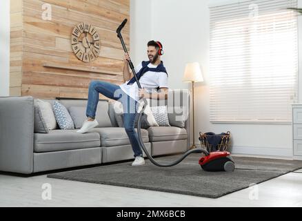 Young man having fun while vacuuming at home Stock Photo
