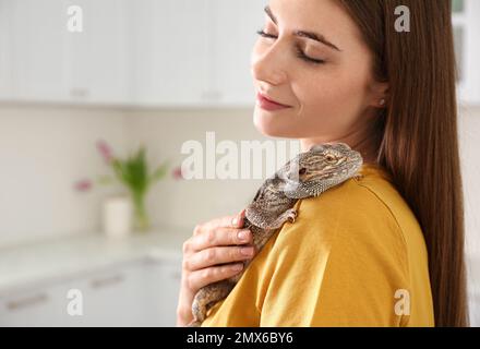 Woman holding bearded lizard in kitchen. Exotic pet Stock Photo
