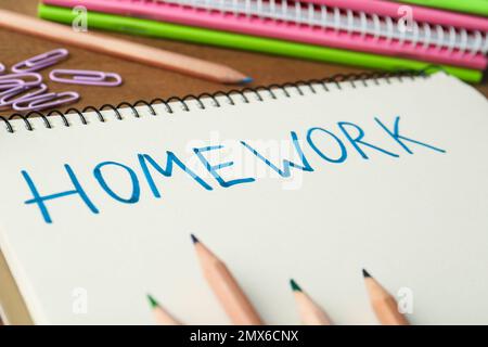 Word HOMEWORK written in notebook on wooden table, closeup Stock Photo