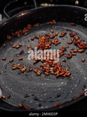 Cooking rice in a pan on a dark background. Toned. Stock Photo