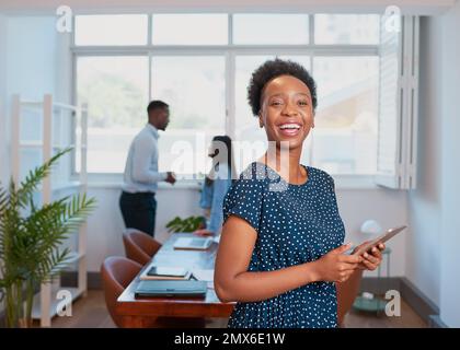 Young Black woman laughs in boardroom office using digital tablet Stock Photo