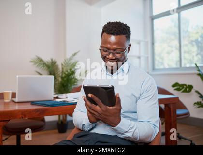 Young Black businessman uses digital tablet smiling in conference room office Stock Photo