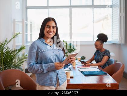 Young business woman using tablet, colleague in boardroom office space Stock Photo
