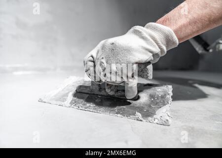 spreading the insulation on the concrete with a trowel Stock Photo